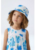 Vista con modelo Sombrero de sol para niñas con diseño reversible y estampado de flores en tonos azules.