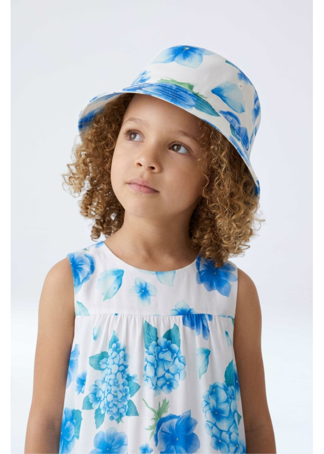 Vista con modelo Sombrero de sol para niñas con diseño reversible y estampado de flores en tonos azules.